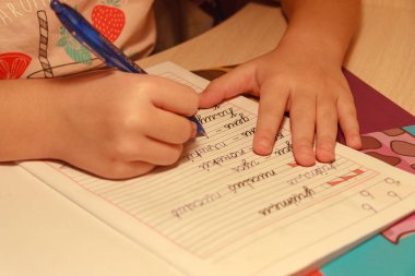 Kız onun elinde kalem tutan ve kelimeler bir not defterinde yazıyor