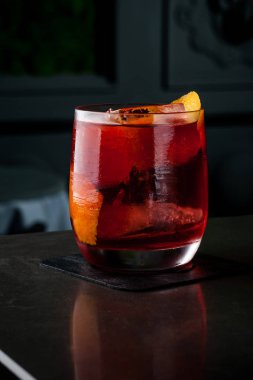 Barmen turuncu ve buz bir kokteyl yapar. Makro, siyah arka plan, el, kırmızı