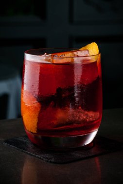 Barmen turuncu ve buz bir kokteyl yapar. Makro, siyah arka plan, el, kırmızı