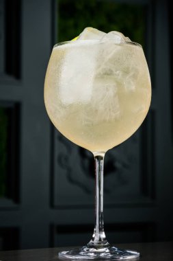 bir barmen bir yaz buz ve kireç kokteyl yapar. Makro, siyah arka plan, el, sarı, damla cam, bubbles