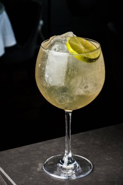 bir barmen bir yaz buz ve kireç kokteyl yapar. Makro, siyah arka plan, el, sarı, damla cam, bubbles