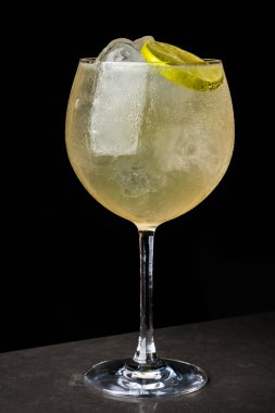 bir barmen bir yaz buz ve kireç kokteyl yapar. Makro, siyah arka plan, el, sarı, damla cam, bubbles