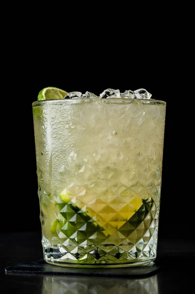 Cold cocktail with lime and lemon. A glass of dew drops. Freshness, alcohol, bar. Black background — Stock Photo, Image