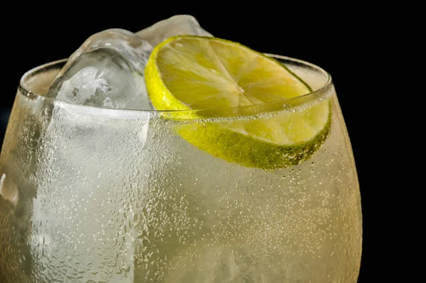 bir barmen bir yaz buz ve kireç kokteyl yapar. Makro, siyah arka plan, el, sarı, damla cam, bubbles