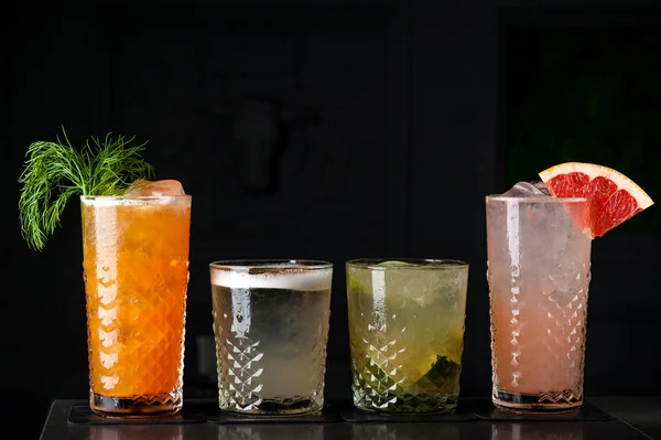 havuç kokteyl otlar bir bardak buz ile. Bubbles ve çiğ bir parlak yeşil renkte siyah bir zemin üzerine kokteyl