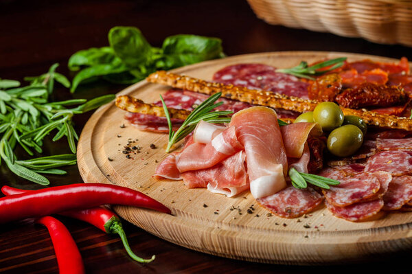 meat sliced proshto, salami, olives and pepper paprika on a wooden plate