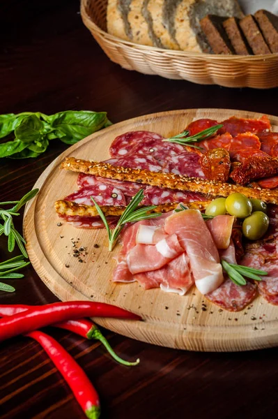 Carne proshto fatiado, salame, azeitonas e pimentão páprica em uma chapa de madeira — Fotografia de Stock
