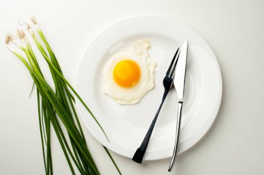 Çatal ve bıçak beyaz tabakta omlet. Plaka yakınındaki yeşil soğan.