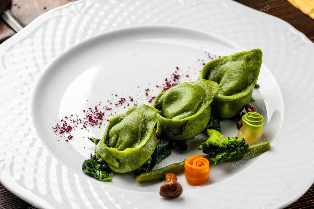 Green Ravioli with quail egg. A Halloween Feast. Black brick wall background and wooden table