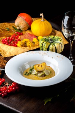 Som balık ile kabak krem çorbası Cadılar Bayramı kutlamaları için bir restoranda bir yemek. Siyah arka plan, tuğla duvar ve ahşap masa