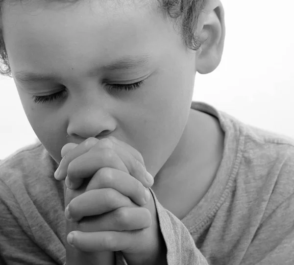 boy praying to God with hands together and closed eyes on white background