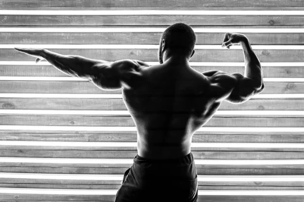 Atleta Africano Masculino Demuestra Los Músculos Sobre Fondo Madera Lámparas — Foto de Stock