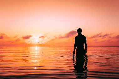 Gün batımında sudaki bir adamın silueti.