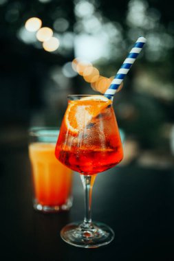 Bir bardak Aperol Spritz ve mavi pipet, İtalyan Kokteyli. İnce film tahıl dokusu.
