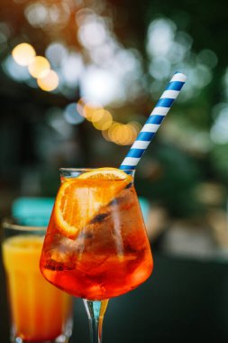 Bir bardak Aperol Spritz ve mavi pipet, İtalyan Kokteyli. İnce film tahıl dokusu.