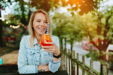 İtalyan kokteyli içen genç bir kadın, Aperol Spritz. İnce film tahıl dokusu.