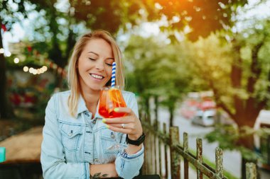İtalyan kokteyli içen genç bir kadın, Aperol Spritz. İnce film tahıl dokusu.