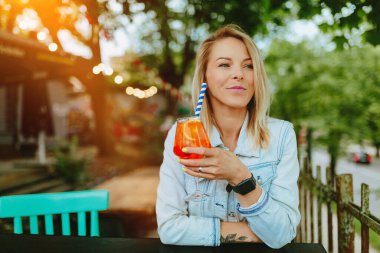 İtalyan kokteyli içen genç bir kadın, Aperol Spritz. İnce film tahıl dokusu.