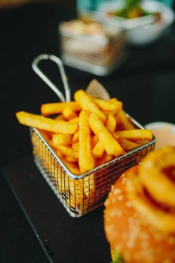 Kafe masasında bir sepet kızarmış patates. Yumuşak odaklanma, iyi film kazanım dokusu.