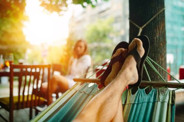 Hamakta dinleniyor. Parmak arası terlikli erkek ayakları. Yumuşak odaklanma, iyi film kazanım dokusu.