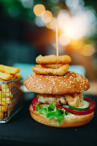 Burger and French Fries and onion rings on cafe table. Soft focus, fine film gain texture.