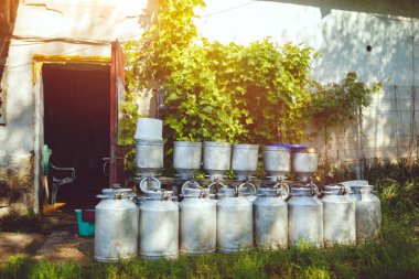 Kırsal kesimdeki çiftlikteki ahırın yanında duran antika süt kutuları.