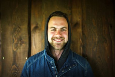 Ahşap duvarın önünde gerçek bir genç adam portresi, doğal ışık..