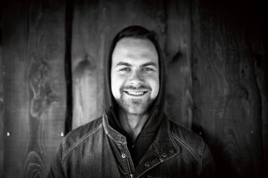 Ahşap duvarın önünde gerçek bir genç adam portresi, doğal ışık..