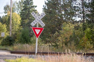 Demiryolu kavşağında yeşil ve kırmızı bir tabela var.