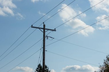 Mavi gökyüzünün arka planında yüksek voltaj direği ve kablolar