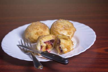 Taze erik köfte. Bir dilimlenmiş dumpling ve bıçak ve çatal koyu kırmızı masada beyaz tabakta ile iki tüm.