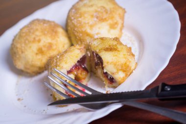 Taze erik köfte. Bir dilimlenmiş dumpling ve bıçak ve çatal koyu kırmızı masada beyaz tabakta ile iki tüm.