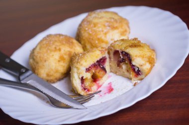 Taze erik köfte. Bir dilimlenmiş dumpling ve bıçak ve çatal koyu kırmızı masada beyaz tabakta ile iki tüm.