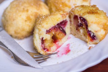 Taze erik köfte. Bir dilimlenmiş dumpling ve bıçak ve çatal koyu kırmızı masada beyaz tabakta ile iki tüm.