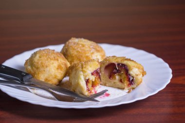 Taze erik köfte. Bir dilimlenmiş dumpling ve bıçak ve çatal koyu kırmızı masada beyaz tabakta ile iki tüm.