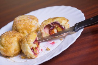 Taze erik köfte. Bir dilimlenmiş dumpling ve bıçak ve çatal koyu kırmızı masada beyaz tabakta ile iki tüm.