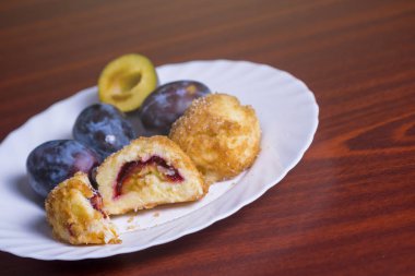 Taze erik köfte. Bir dilimlenmiş dumpling ve koyu kırmızı masada beyaz tabakta taze erik ile bir bütün.