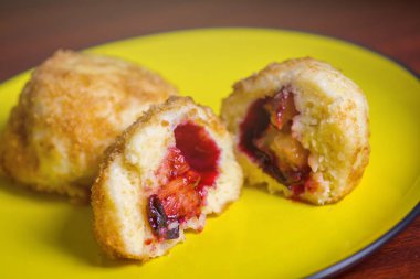 Taze erik köfte. Bir dilimlenmiş dumpling ve koyu kırmızı masada sarı plaka üzerinde bir delik.