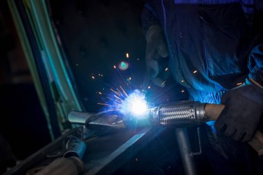 Erkek işçi araba egzoz boru kaynak makinesi ile kısayollarımı koruyucu eldivenler