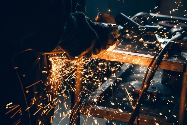 Close up of car mechanic hands welding grinding machine.Sparks of grinding machine while cutting car exhaust pipe