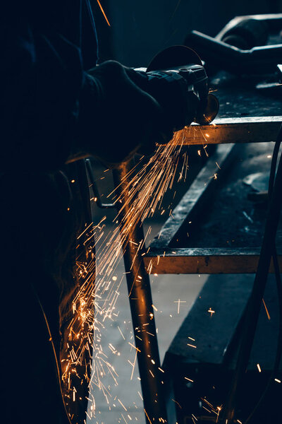 Close up of car mechanic hands welding grinding machine.Sparks of grinding machine while cutting car exhaust pipe