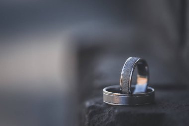 Beyaz altın alyans siyah kaya üzerinde durmak. Arka plan bulanık.