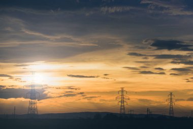 Yüksek gerilim ızgaralı pilon hatta parti bulut günbatımı