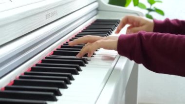 Beyaz ahşap piyano üzerinde kırmızı kazaklı elinde genç kız