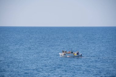 Açık denizde bir adam ile küçük beyaz motorlu tekne yelken.