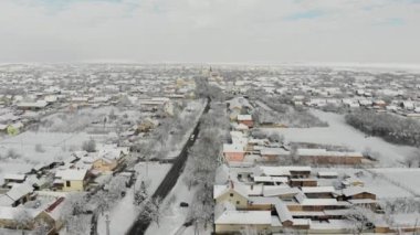 Uçak 4k düz köyde hava görüntülerini karla kaplı. Beyaz bulutlu kış hava.