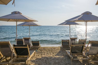 Şemsiye ve satır arka planda mavi deniz suyu ile düzenlenmiş sandalyeler