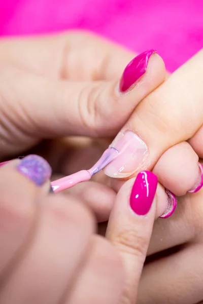 Manicurist polish nails on women\'s hand in nail salon.