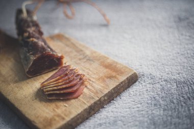 Bir ahşap tahta üzerinde kurutulmuş bir jambon aperatifler kesilmiş.