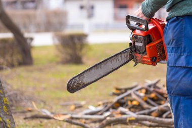 Mavi pantolonlu yaşlı adam tutun turuncu chainsaw kendi elleriyle.